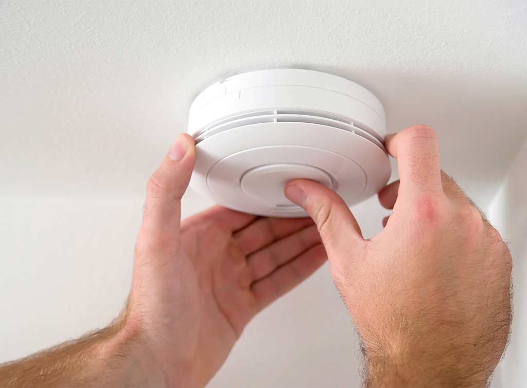 Smoke alarm installer fitting ceiling-mounted smoke detector in Clapham - SW4